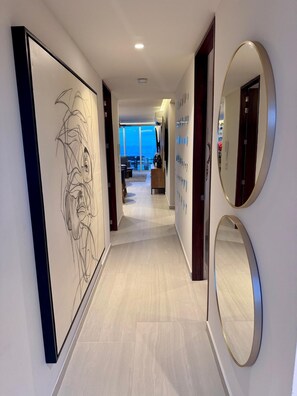 A modern hotel hallway with a large abstract painting, circular mirrors, and a view to a balcony area. - Oceana Luxury Escape | 3BR/3BA | Ocean Views (Bucerias)