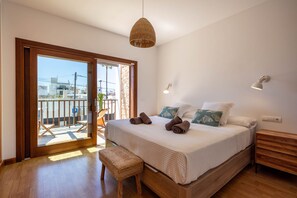 A bedroom with a bed, bedside tables, a bench, a hanging light, and a view through a glass door. - Casa Victoria | Ibiza town 5 min (Islas Baleares)