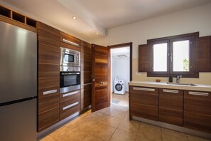 A modern kitchen with wooden cabinets, stainless steel appliances, and a built-in oven. - Casa Victoria | Ibiza town 5 min (Islas Baleares)