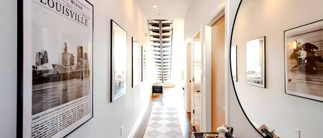 Walk through this stylish hallway featuring a bold checkerboard runner and a collection of stunning local photography. The giant round mirror at the end is perfect for one last outfit check before heading out.