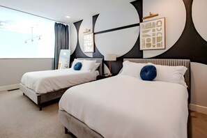 Drift off to sleep in these twin beds backed by a bold black and white geometric circle mural. The soft blue throw pillows add a cozy and calming touch to the room. - Gorgeous NuLu Retreat | Gated Parking | Two Patios (Louisville)