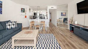 Un salon moderne comprenant un canapé, une table basse et un coin repas avec des chaises.