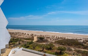 A beach view from a balcony with a sandy beach, ocean, and sparse vegetation. - Beachfront 1 BR 1.5 BA Unit with a Pool and Fantastic Ocean Views! (Ocean City)