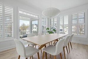 Une salle à manger avec une grande table en bois, six chaises et un luminaire suspendu.