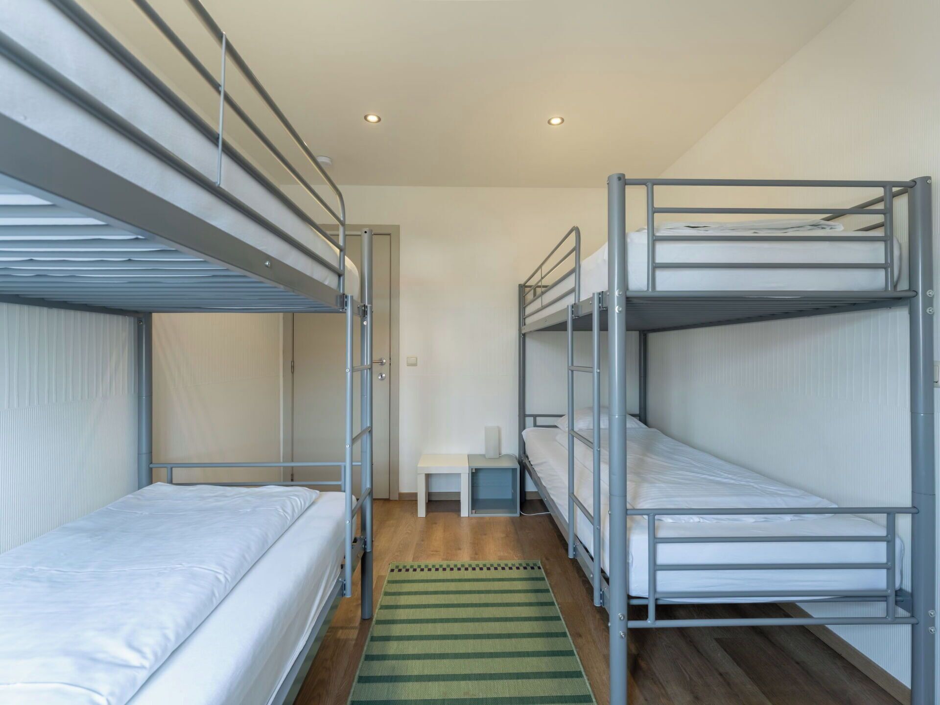 A room with bunk beds, a small table, and a green rug.