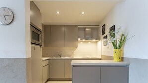 Uma cozinha moderna com ilha central, iluminação embutida e um relógio na parede.