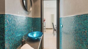 Ein Badezimmer mit einem blauen Waschbecken aus Glas, einem weißen Handtuch und einem Spiegel an der Wand.