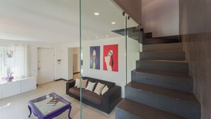 Ein modernes Wohnzimmer mit einer Glaswand, einer Treppe und einem Sofa.