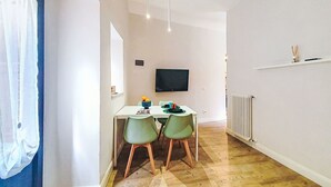A dining area with a table, chairs, a television, and a radiator.