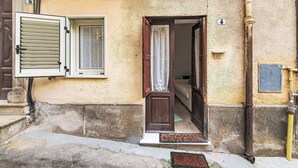 A building entrance with a wooden door, a window with shutters, a doormat, and a sign reading 'VIA PIAVE'.