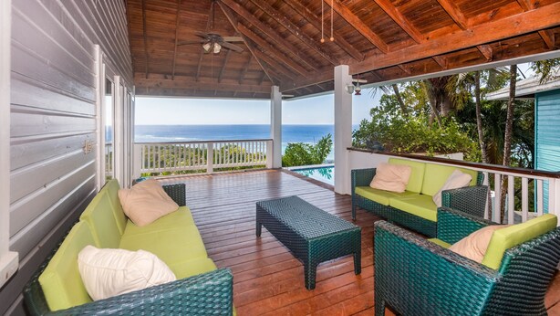 A covered outdoor seating area with wicker furniture and a view of the ocean. - Top Ridge Views 2 Bedroom Home (Roatan)
