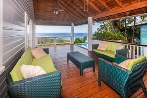 A covered outdoor seating area with wicker furniture and a view of the ocean. - Top Ridge Views 2 Bedroom Home (Roatan)