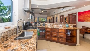 Una cucina moderna con piani in granito, cappa in acciaio inossidabile e una grande isola con cassetti in legno.
