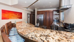 Una cucina con piani in granito, elettrodomestici in acciaio inossidabile e una grande isola con posti a sedere.
