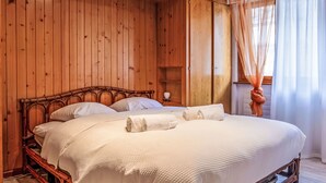 Un dormitorio con paneles de madera, una cama, almohadas y una mesita de noche.