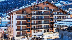 Un hotel de varios pisos con balcones y montañas al fondo.