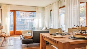 Una sala moderna con comedor, ventanas grandes y vistas a edificios.