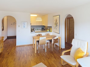 Ein modernes Wohnzimmer mit Essbereich, Holzboden und einer Küche im Hintergrund.