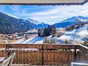 Ein Balkon mit Blick auf schneebedeckte Berge und ein bewaldetes Tal.