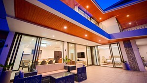 Un immeuble résidentiel moderne à plusieurs niveaux, doté de portes vitrées, d’un espace repas et d’une chambre.