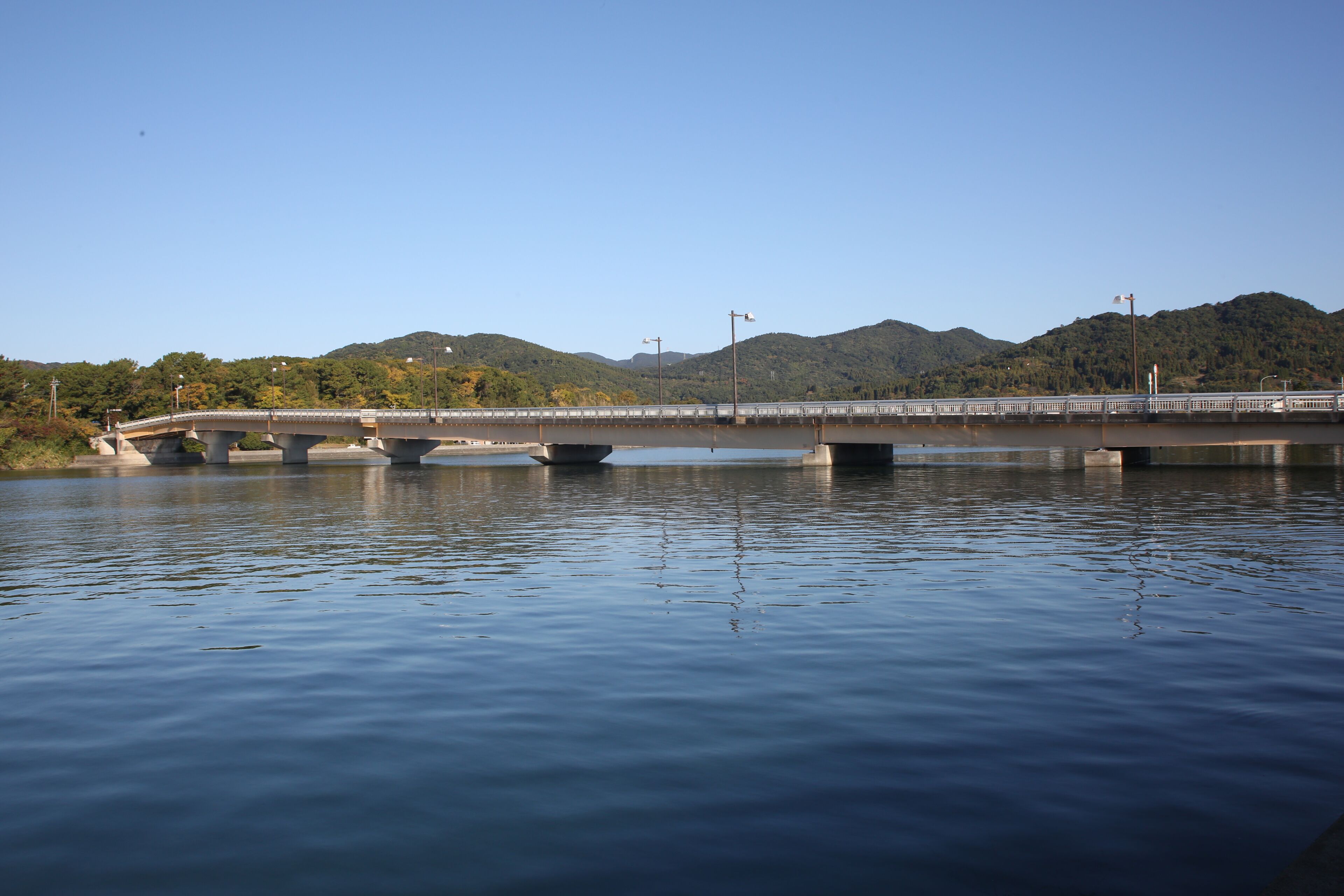 Un puente sobre aguas tranquilas con una montaña al fondo.