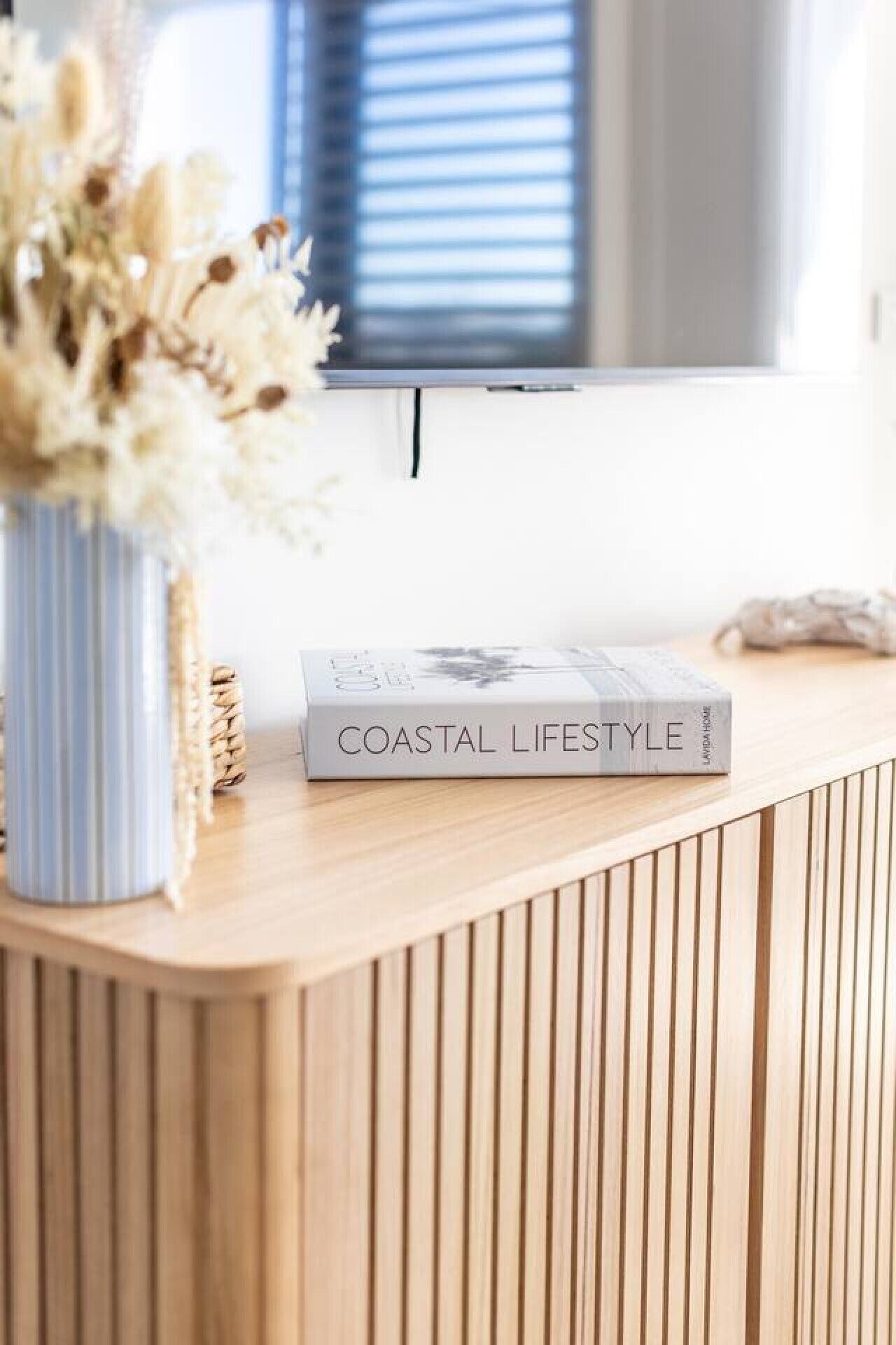 A wooden reception desk with a book titled 'COASTAL LIFESTYLE' on it.
