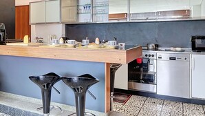Eine moderne Küche mit einer Holzausziehtafel, Edelstahlgeräten und einem Barhocker.