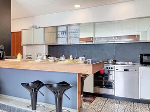 A modern kitchen with a wooden countertop, stainless steel appliances, and a bar stool. - Villa Bikini by Interhome (St-Gingolph)