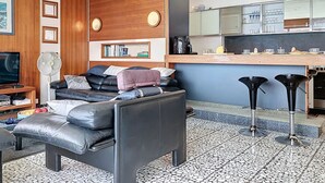 Ein modernes Wohnzimmer mit einer Couch, einer Kaffeemaschine und einer Küchenzeile mit Barhocker.