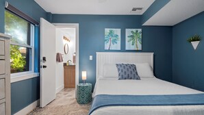 A bedroom with a bed, a nightstand, a window, and a door. - Oceanfront Ground Level Apt | Patio + Beach Access (St. Augustine)