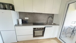 A modern kitchen with white cabinets, a stainless steel sink, an oven, and a microwave. - Southwest Ljubljana Private Parking 8 (Ljubljana)