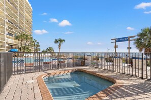 Ein Hotelpoolbereich mit freiem Blick auf den Pool, Palmen und ein Gebäude im Hintergrund.