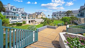 A residential complex with multiple two-story buildings, a central courtyard with seating, and a green lawn. - New to VRBO 3 Bedroom Villa - Golf cart included - 604 Newhaven (Fripp Island)