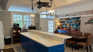 A kitchen with a central island, a dining area with a wooden table and chairs, and a ceiling fan. - Huge Private Pool, Single Level Easy Access, 2 Golf Carts Included, Pet Friendly - 276 Tarpon Blvd (Fripp Island)