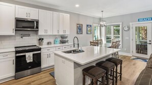 Una cocina moderna con gabinetes blancos, electrodomésticos de acero inoxidable y una isla grande con taburetes de bar.
