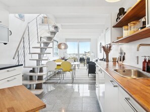 Een moderne keuken met een houten aanrecht, een roestvrijstalen spoelbak en een spiltrap.