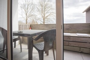 A patio with a table and chairs, a wooden bench, and a view of trees through a glass door. - Apartment - Winterbergerstrasse 3 nr 505 (Winterberg)
