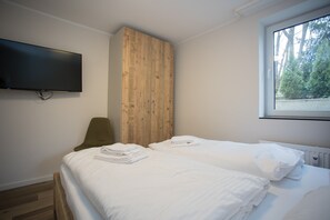 A hotel room with a bed, a television mounted on the wall, and a window with a view of trees. - Apartment - Winterbergerstrasse 3 nr 505 (Winterberg)