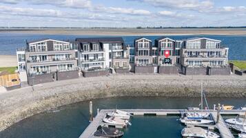 Een pand aan het water met moderne architectuur, een jachthaven met boten en uitzicht op de zee.
