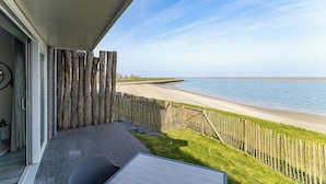 A balcony with a view of a beach and wind turbines in the distance.