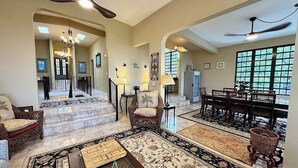 A spacious living area with a high ceiling, a dining area with wooden furniture, and a staircase leading to another level. - Vieques BioBay B&B, The Horse Room:Sleep Under the Stars, Paddle the Glowing Bay (Vieques)