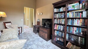 Una sala de estar con un sofá, una mesa de centro, una televisión y una estantería llena de libros.