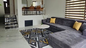 Een moderne woonkamer met een grijze bank, een vloerkleed met een patroon en een marmeren vloer.