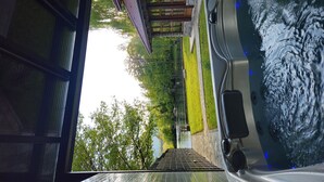 Een hottub met een stenen muur en een houten terras.