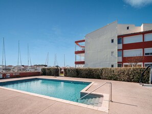 A swimming pool with steps leading into it, surrounded by a hedge and a building with balconies. - Quiet Elegance Near the City Center Agde (Agde)