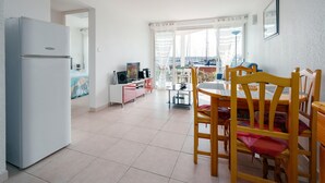 A modern kitchen with a white refrigerator, a dining area with wooden chairs and a table, and a view of the marina through large windows. - Quiet Elegance Near the City Center Agde (Agde)
