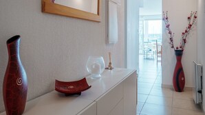 A modern interior with a white console table, a mirror, and two vases with branches. - Quiet Elegance Near the City Center Agde (Agde)