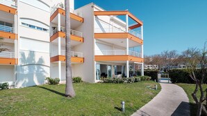 A multi-story building with balconies, a pathway, and a palm tree. - Quiet Elegance Near the City Center Agde (Agde)