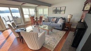 A living room with a sofa, coffee table, and chairs, a fireplace, and a view of the outdoors. - Golden View lake house on Crawford Pond (Union)