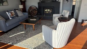 A living room with a sofa, armchairs, a coffee table, a fireplace, and a clock. - Golden View lake house on Crawford Pond (Union)